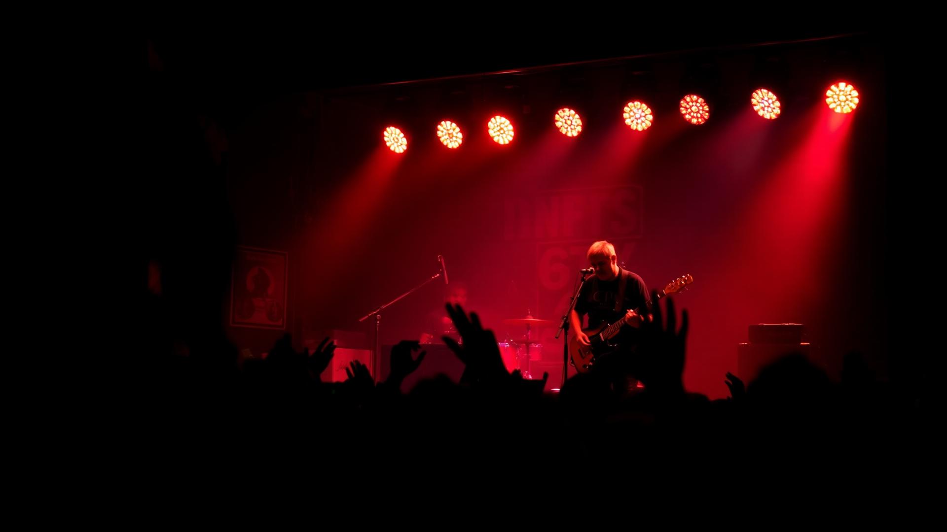 Live band performing under red stage lights in a packed club